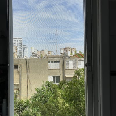 חלון אלומיניום עם נוף חיצוני של בניינים ועצים