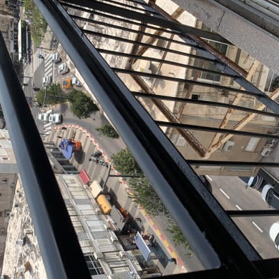 מעקה ברזל שחור עם סורגים מעל רחוב עירוני