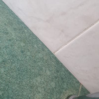 ברז מתכת על משטח ירוק ליד קיר לבן