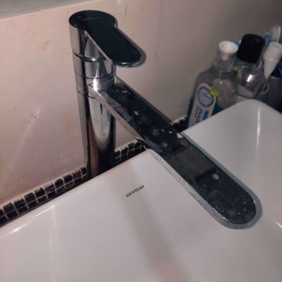 ברז כרום עם כתמי מים על כיור לבן