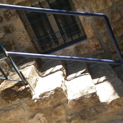 מעקה מתכת כחול על מדרגות אבן