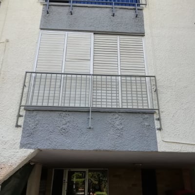 מרפסת עם מסגרת מתכת ותריסים לבנים