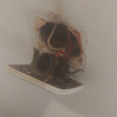 שקע חשמלי פתוח עם חוטים חשופים בקיר