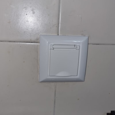 שקע חשמלי עם כיסוי על קיר אריחים לבן