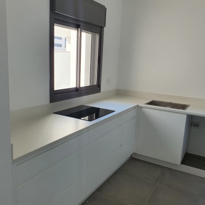 מטבח עם משטח שיש לבן וכיריים שחורות