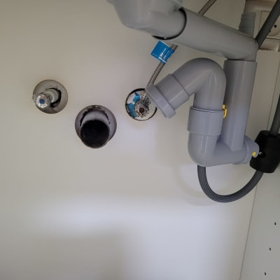 צינורות פלסטיק אפורים מתחת לכיור עם מחברים