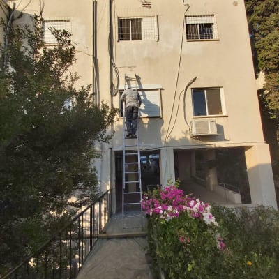 אדם על סולם אוטם קיר חיצוני של בניין