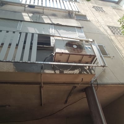 יחידת מיזוג אוויר מותקנת על קיר חיצוני עם צינורות.