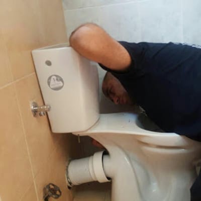 אדם מתקן אסלה בחדר אמבטיה