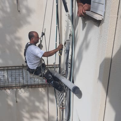 אדם על חבל מתקן צינור חיצוני עם תרסיס