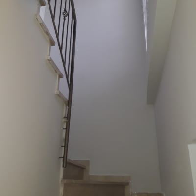 קיר צבוע בלבן ליד מדרגות עם מעקה מתכת