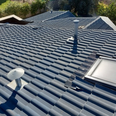 רעפים אפורים עם ארובה וחלון גג על גג בית