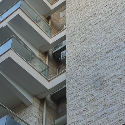 בניין עם מרפסות זכוכית וצינורות חיצוניים