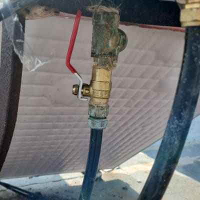 שסתום מתכת עם ידית אדומה בצינור דוד שמש