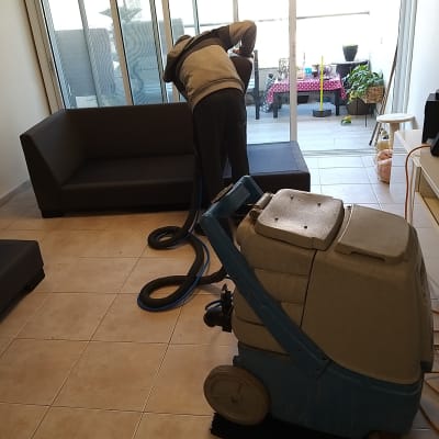 אדם מנקה ספה עם מכונת ניקוי מקצועית