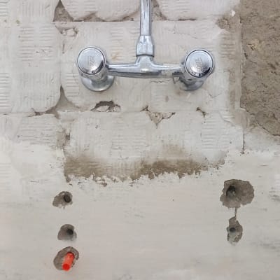 ברז מותקן על קיר עם חורים ושאריות טיח