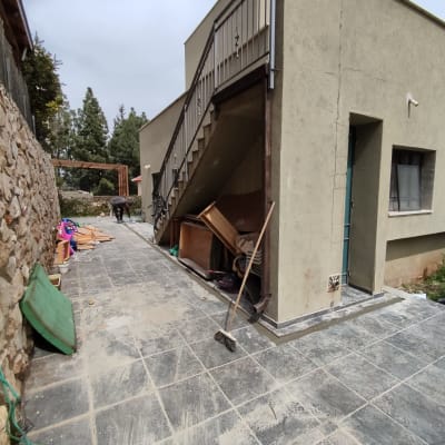 אדם עובד בחוץ ליד בית עם כלים שונים