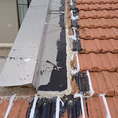 גג רעפים עם תיקוני איטום בצבע שחור ולבן