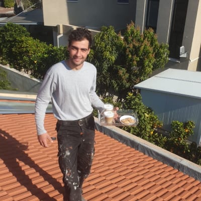 אדם עומד על גג רעפים אדום עם כוסות קפה ועוגיות.