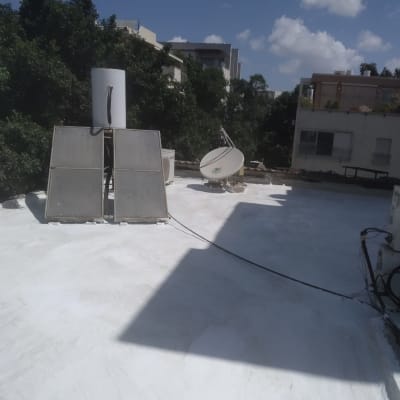 גג אטום בלבן עם צלחות לוויין ודודי שמש