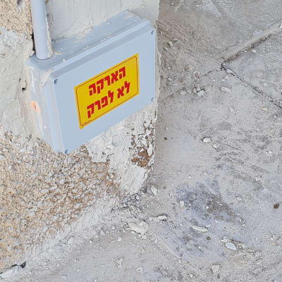 קופסת חשמל עם שלט אזהרה על קיר