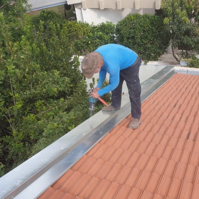 אדם קודח על גג רעפים עם מקדחה חשמלית