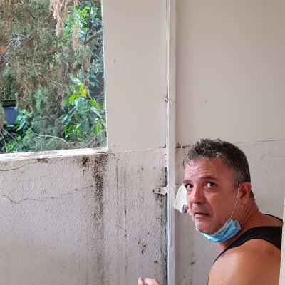 אדם עם מסכה ליד קיר מתקלף