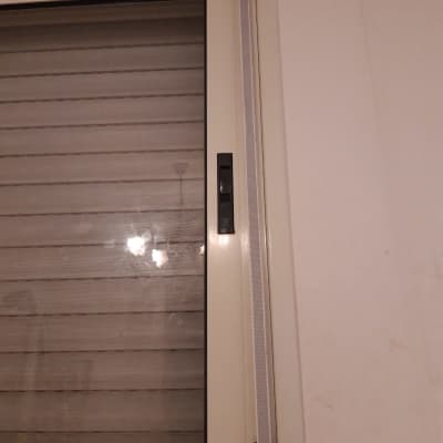 תריסים סגורים עם ידית שחורה על מסגרת לבנה