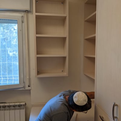 נגר עובד על התקנת מדפים בחדר קטן
