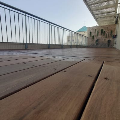 רצפת עץ עם מעקה מתכת וצמחים על קיר