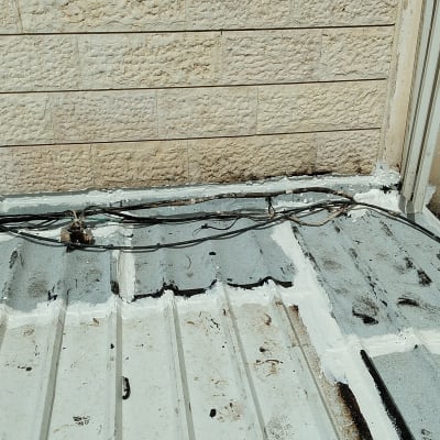 איטום גג עם חומר לבן ואפור סביב כבלים
