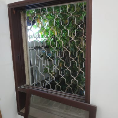 חלון עם מסגרת חומה ורשת מתכת