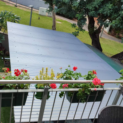 גג מתכת עם עציצים ופרחים אדומים על מעקה