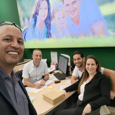 יועץ משכנתאות עם לקוחות במשרד, מחשבים וניירת על השולחן