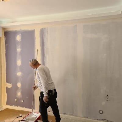 אדם מורח טיח על קיר גבס עם רולר