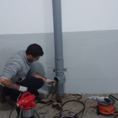 אדם עובד על צינור ביוב עם כלים