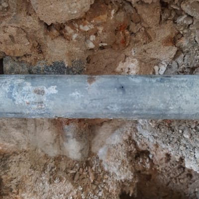 צינור מתכת בתוך קיר עם אדמה חשופה