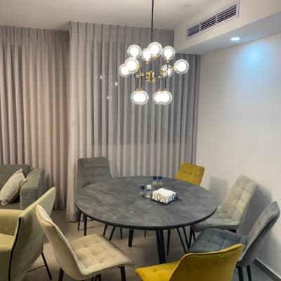 וילון לבן ארוך תלוי על הקיר ליד שולחן עגול