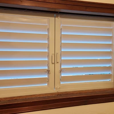 תריסי אלומיניום לבנים בחלון עץ