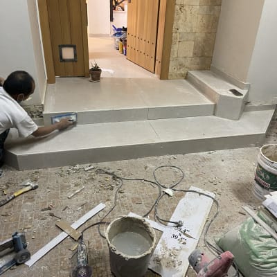 עובד משפץ מדרגות עם כלי עבודה וחומרי בניין