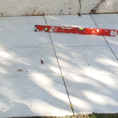 אריחים מונחים על הקרקע עם פלס ומטר מדידה