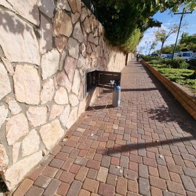 מיכל גז ליד קיר אבן על מדרכה
