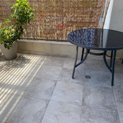 מרפסת עם ריצוף חדש ושולחן זכוכית עגול