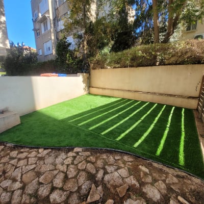 דשא סינתטי מונח על הקרקע בחצר קטנה