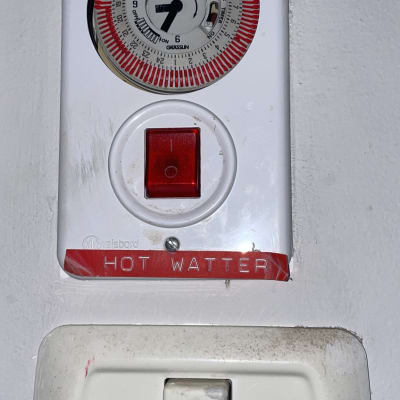 שעון טיימר ומתג חשמלי על קיר לבן