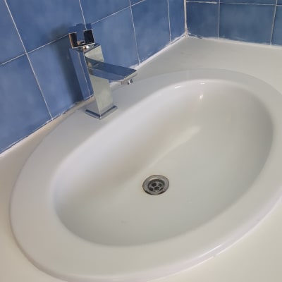 כיור לבן עם ברז כרום על רקע אריחים כחולים