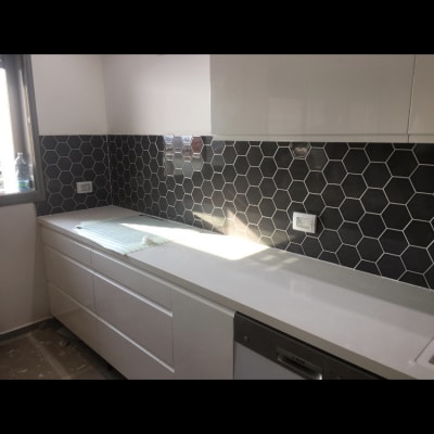 מטבח עם אריחים משושים שחורים ומשטח עבודה לבן