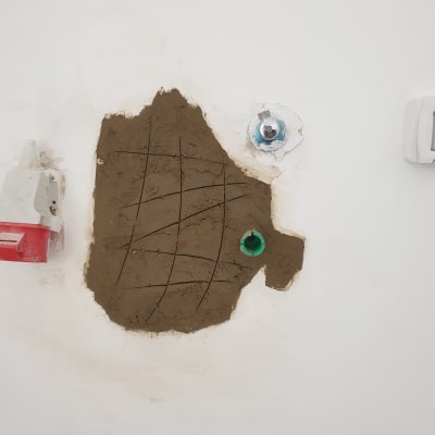 קיר עם חור ותשתית צנרת חשופה