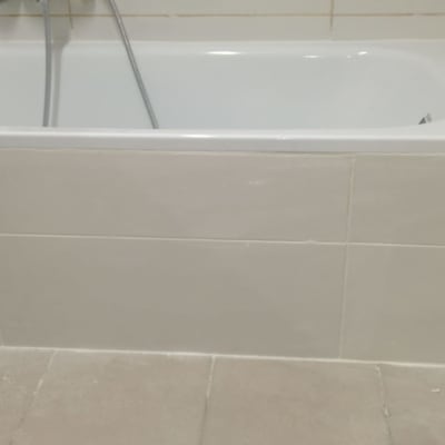 אמבטיה עם אריחים לבנים וברז מקלחת