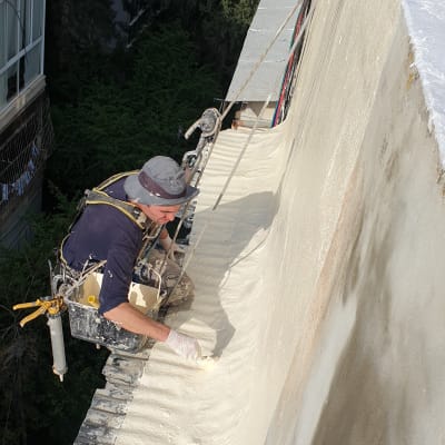 אדם מורח חומר איטום על קיר חיצוני